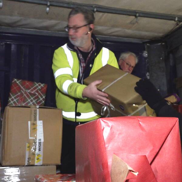 Tre äldre män från Sam-hjälp packar in julklappar i en lastbil.