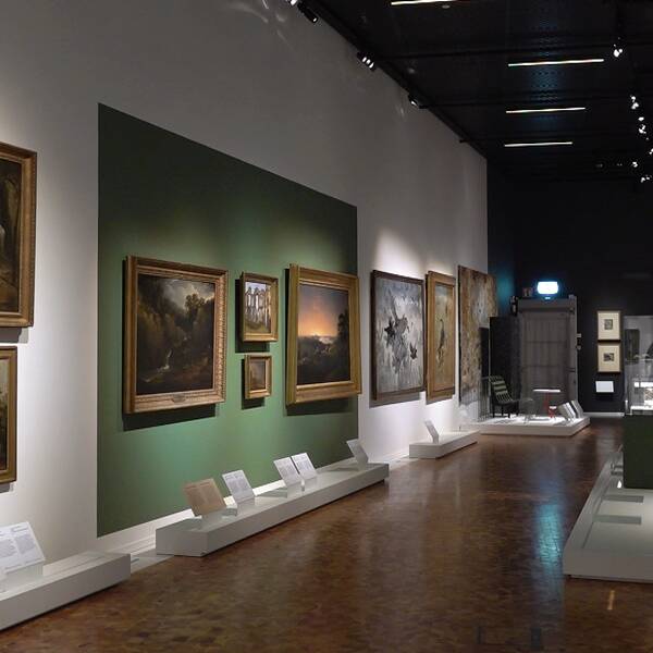 Det blir ingen ny utställning på Nationalmuseum Jamtli nästa år, när pengar ska sparas. På bilden ser man en utställningslokal med tavlor på väggarna.