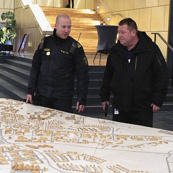 På bilden ser du en polis och Kirunas säkerhetschef Jan Lundmark framför en enorm karta på kommunen.