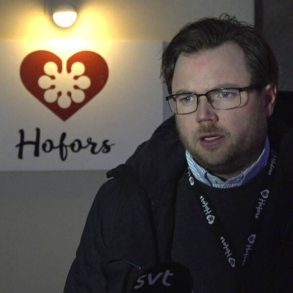Man i glasögon och skägg framför en upplyst skylt där det står Hofors.