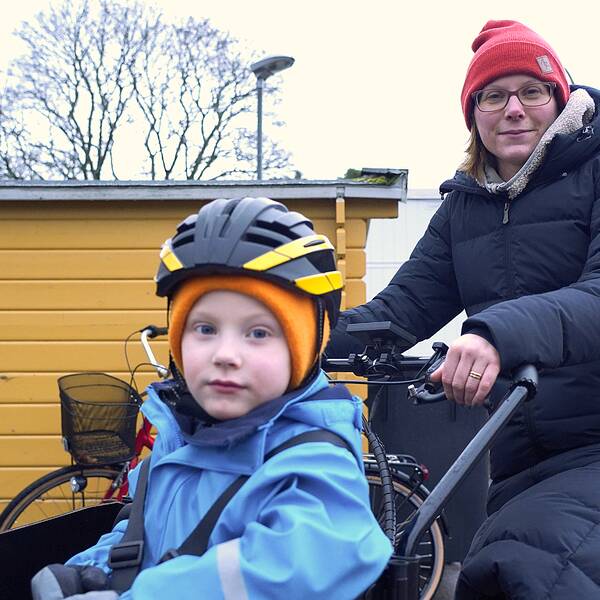 Halvbild på mamma Sofia Hedlund på cykel, i lådvagnen är sonen Albin.