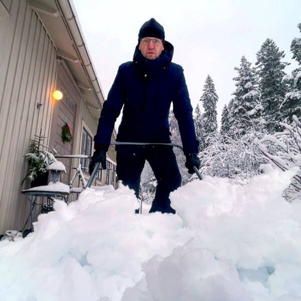 En man (SVT:s reporter Fredrik Israelsson) står ute i vinterlandskap och skottar snö