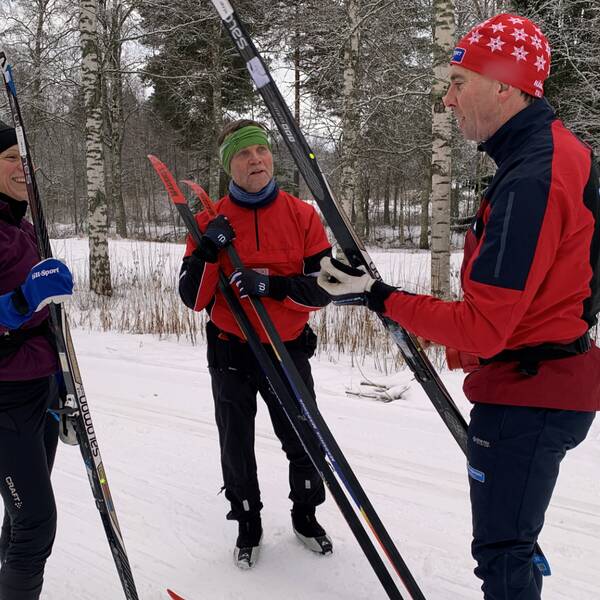 Två skidåkare, en man och en kvinna, får instruktioner av en skidinstruktör i skidspåren