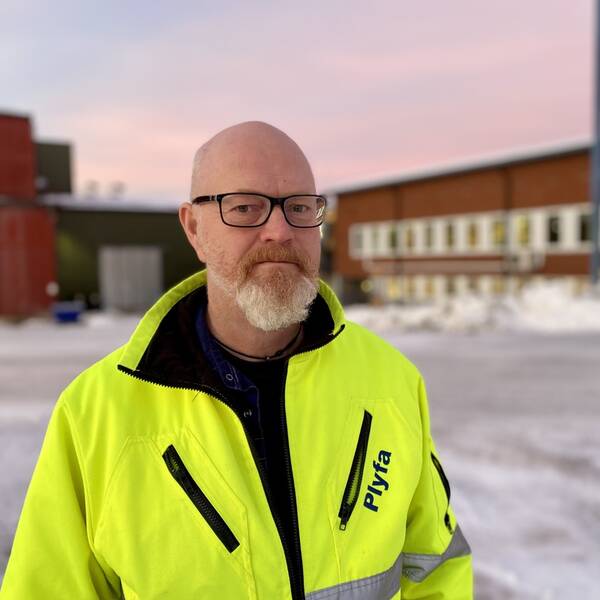 Svarvaren Mikael Nordström står utanför fabriken Plyfa med reflexjacka i soluppgången.