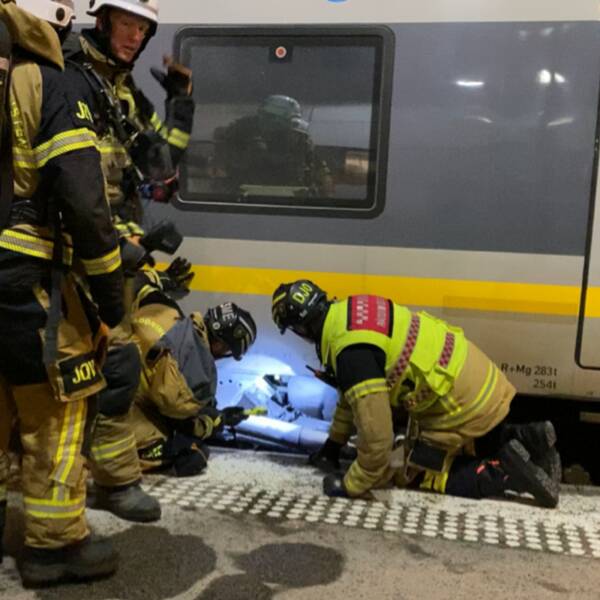 Brandmän som lyser med ficklampa under ett tåg.