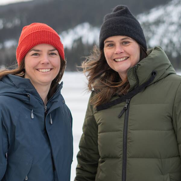 Två kvinnor med långt mörkt hår i vinterkläder som ler in i kameran.