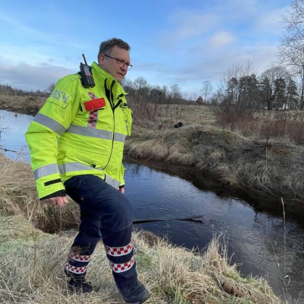 Micael Holmstrand från räddningstjänsten i Ljungby visar hur fåran vid ån Lagan i Hamneda ska byggas.