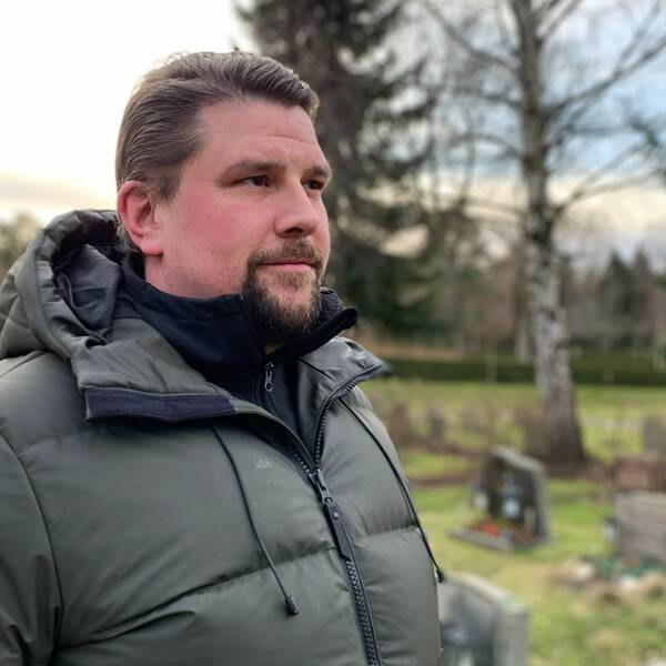 Daniel Sandberg står på kyrkogården vid St Eskil utanför Eskilstuna. I bakgrunden syns gravstenar och träd.