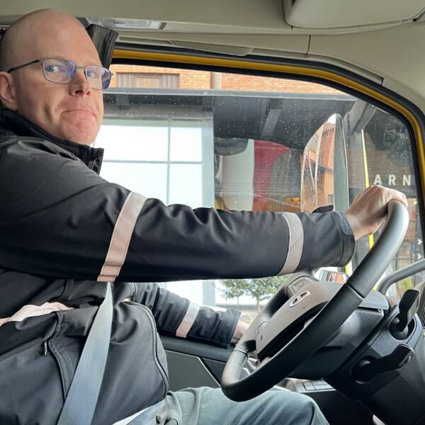 Christian Robertsson, som kör lastbil i Huskvarna, sitter i sin lastbilshytt med händerna på ratten och kollar rätt in i kameran.