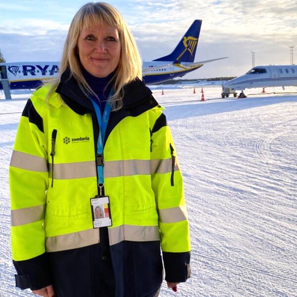 Ann-Christin Viklund poserar nere på flygdäcket framför två olika plan hemmahörande på Luleå airport.