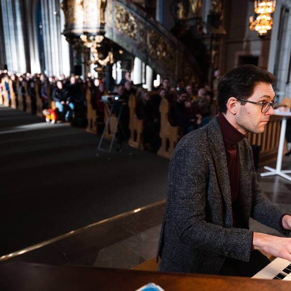 organisten Robert Bennesh spelar orgel i en duell i Uppsala domkyrka, medan publiken hör på i bänkarna