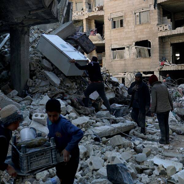 Människor hjälps åt med att bära bort möbler från en förstörd byggnad i Jinderis i Syrien. 