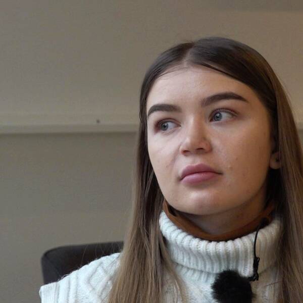 Ung kvinna tittar ut ur bild med tårar i ögonen.