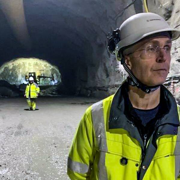 Tre personer är inne i en tunnel under korsvägen. De har gula varselkläder på sig och skyddshjälmar