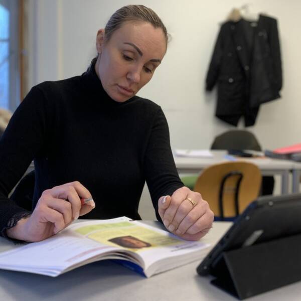 Viktoria Bryseh från Ukraina studer sfi i Vaggeryd. Hon sitter vid en bänk och läser en lärobok.