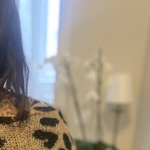 En person bakifrån, vi ser mörkt hår och en vit blomma i bakgrunden.