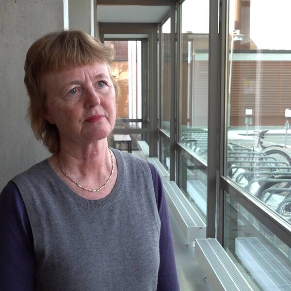 Lisbet Gibson ställföreträdande hälso- och sjukvårdsdirektör står framför en betongpelare och fönster vid Regionens hus i Östersund.