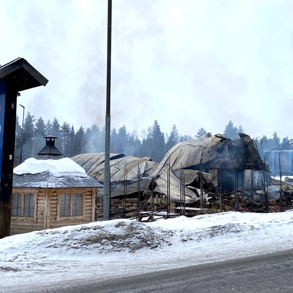 brandruiner som ryker, en skylt som det står Åsarna skicenter på, en flaggstång med en slokande flagga.