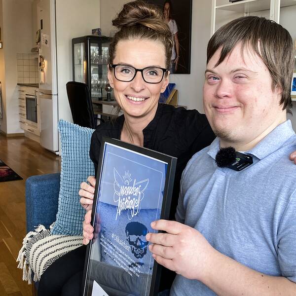 Jonas Wiman och Anna Ginsthammar med priset som de fått för podden #Olikaärbäst, hemma i Jonas lägenhet.