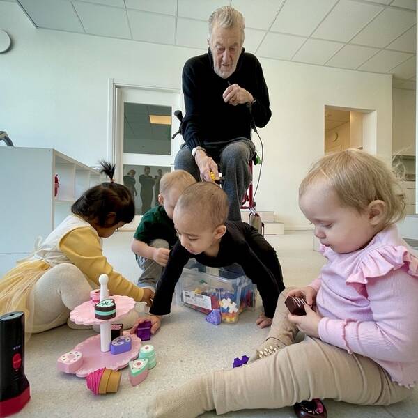 Barn leker och en äldre herre tittar på