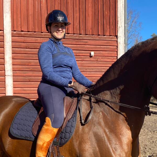 Kvinna som rider på häst i solskenet