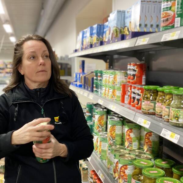 Bild på kvinna framför butikshylla med konserver och glasburkar. Kvinnan heter Annica Mattisson och är lanthandlare i Hällevik.