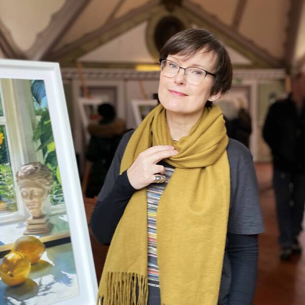 Bild på en målning och besökare i en utställningslokal. Bredvid målningen står en kvinna, som heter CajsaStina Åkerström och är konstnär.