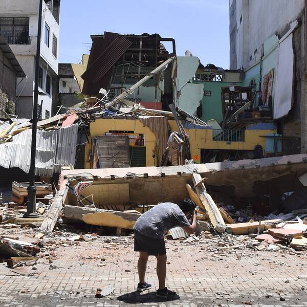 En man tar ett foto av en byggnad som kollapsade efter den jordbävning som skakade bland annat provinshuvudstaden Machala i Ecuador på lördagen.