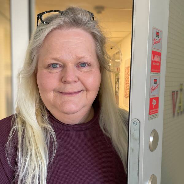 En äldre kvinna i röd tröja står vid dörren och välkomnar in till en BUP-mottagningar.