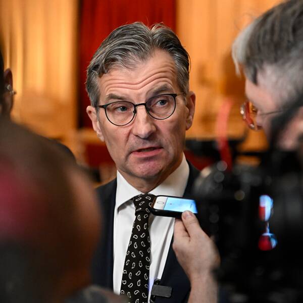 Bild föreställande riksbankchefen Erik Thedéen som syns bakom flera journalister.
