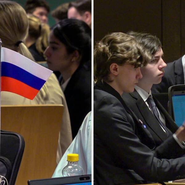 Några ungdomar sitter kring olika bord, Rysslands och Finlands flaggor syns på borden.