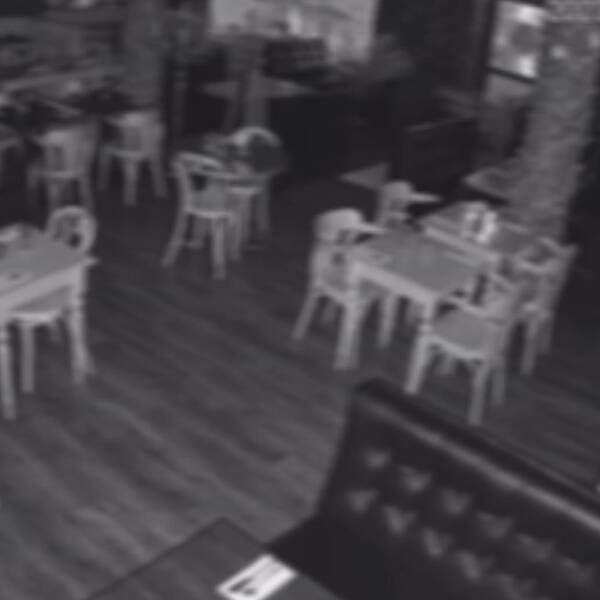 En svartvit något suddig bild inifrån en restaurang.
