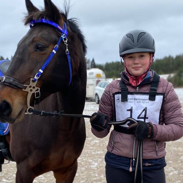 Ett barn står bredvid en brun pony