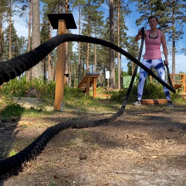 Kvinna som tränar med band i naturen.