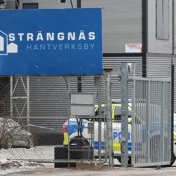 Bild tagen utanför Strängnäs Hantverksby. Man ser ser en skylt med deras logotyp och en polisbil som står bakom grindarna.