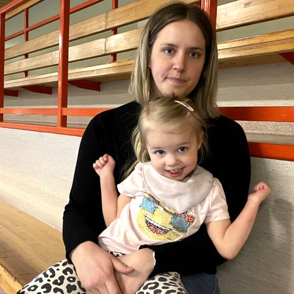 Fyraåriga Ines sitter leende i mammas knä på en läktare.
