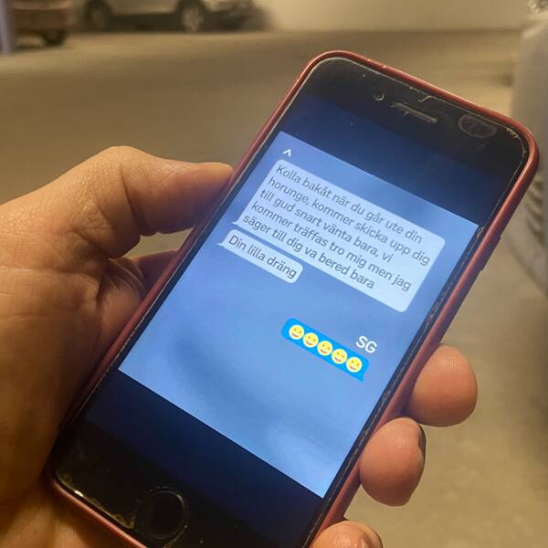 En hand håller i en mobiltelefon med en chattkonversation.