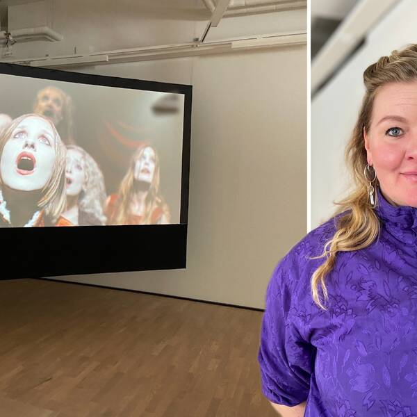 Em kvinna som står framför en stor skärm i en konsthall
