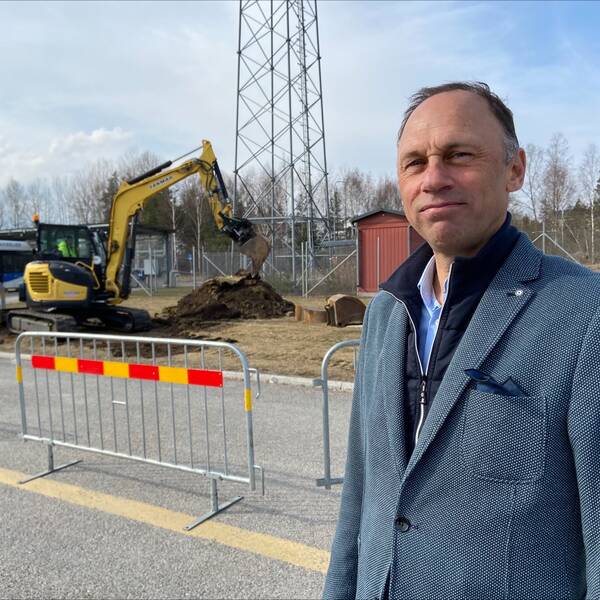 En man står framför en grävskopa.