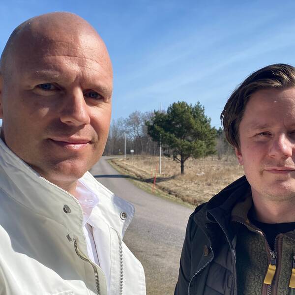 Fastighetsutvecklarna Niklas Johansson och Alexander Lundvall står vid en väg och en golfbana under en solig dag.