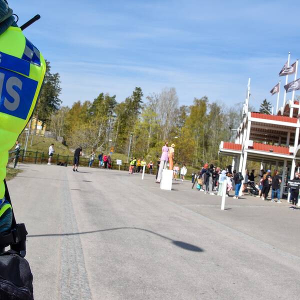 Närbild på polisväst där det står ”dialog polis” till vänster, Furuviksparken syns till höger, människor utanför.
