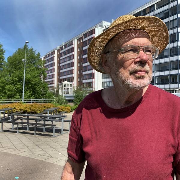 Man i stråhatt framför höghus i miljonprojektsområde.
