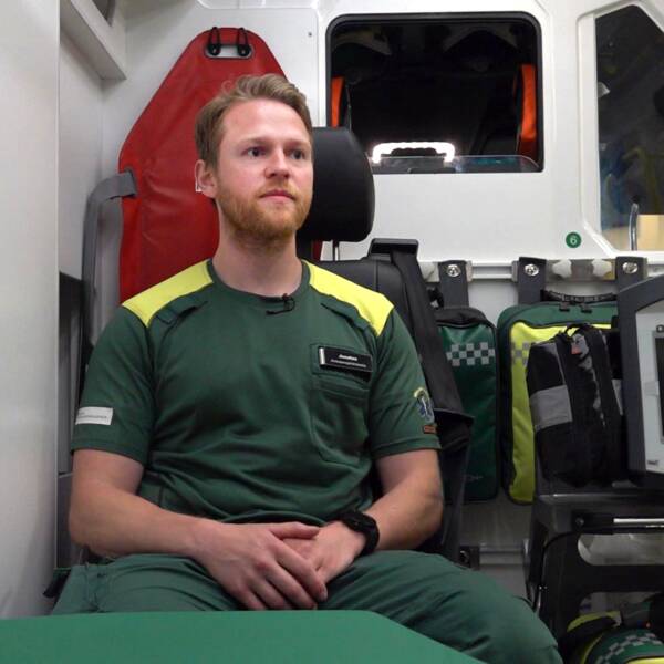 Ambulanssjuksköterskan Jonatan Jardevall sitter i en ambulans. Ung kille med kort hår och skägg.