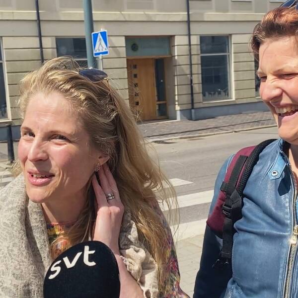 Två kvinnor på gatan i Landskrona, den ena visar upp sina örhängen och den andra skrattar.