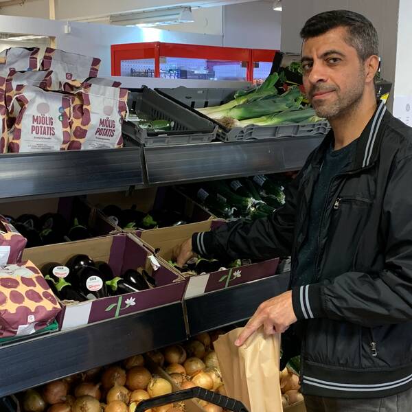 Kunden Husam Matar plockar grönsaker ur en av hyllorna på Matmissionen i Helsingborg.