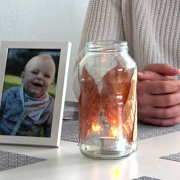 Matteos mamma sitter vid köksbordet vid en ljuslykta och en bild på sin son.
