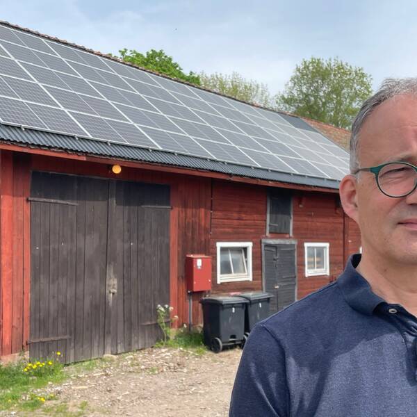 En man står framför ett rött hus.