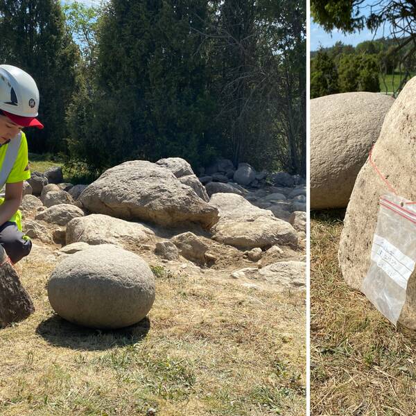 en arkeolog som står vid en sten i form av en fallossymbol.