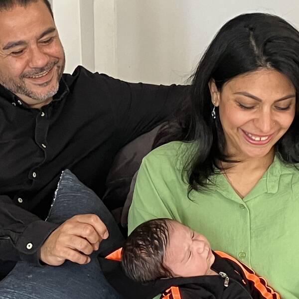 Pappa och mamma med nyfödd bebis i famnen.
