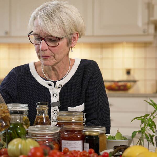 Livsmedelsverkets mikrobiolog Åsa Rosengren står vid ett bord med grönsaker i glasburkar.
